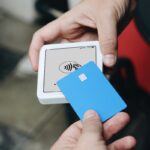 Hands using contactless payment terminal and credit card.